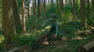 Rider cornering on a trail through the woods on a Marin El Roy mountain bike.
