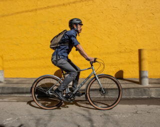 Man riding bike in urban environment with yellow wall